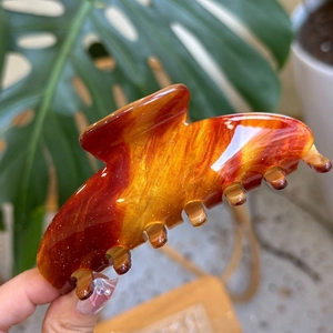 Detail of amber acrylic hair claw with sparkling finish and seven-tooth design