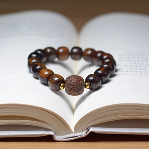 Detailed view of dark brown agarwood beads and carved center bead on an open book
