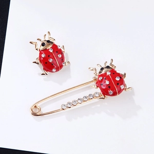 Close-up of gold ladybug brooch with red enamel and sparkling rhinestones on white background