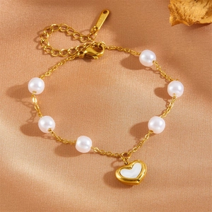 Détail du bracelet en acier inoxydable doré avec perles blanches et pendentif en cœur