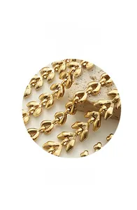 Macro detail of the polished 18k gold-plated wheat-leaf link chain with a textured stone