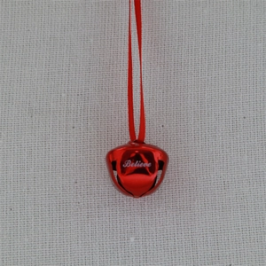 Close-up of a red metal Christmas bell with Believe engraving and a red ribbon