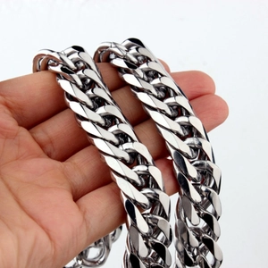 Close-up of a heavy silver stainless steel Cuban link chain necklace held by a hand