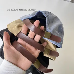 Detail of adjustable leather strap and metal buckle on washed cotton baseball caps