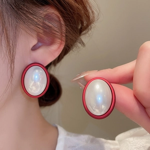Detail shot of vintage matte red oval earrings featuring a glossy white pearl inlay