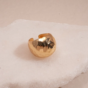 Close-up of golden wide open ring featuring a unique hammered texture on a stone plate