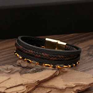 Dettaglio di bracciale multistrato in pelle intrecciata con chiusura magnetica d'oro
