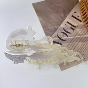 Macro detail of jellyfish acetate hair claw with gold swirls and metallic spring