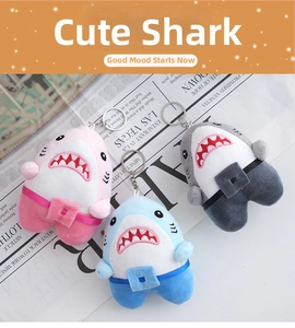 Detailed close-up of shark plush keychains in pink, blue, and grey with cute overalls