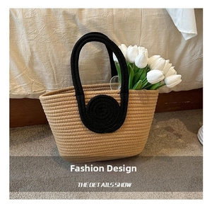 Detail showing the contrast thick black handles and woven cotton rope texture of the tote bag