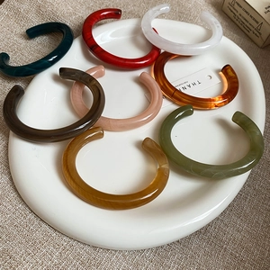 Detail of assorted resin open bangles in various marbled colors on white ceramic plate
