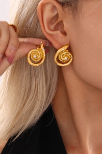 Macro view of gold spiral earrings with inlaid rhinestones worn by a model