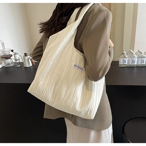 Detail einer weißen Falten-Schultertasche mit KISS YOURSELF Label und Stofftextur