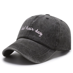 Close-up of pink bad hair day embroidery on washed black cotton baseball cap