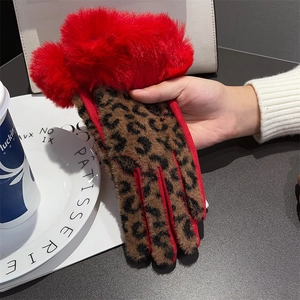 Dettaglio di guanto in peluche leopardato con pompon rosso al polso in stile lifestyle