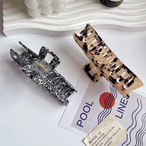 Black spotted and tortoiseshell acetate hair claws shown on minimalist aesthetic props