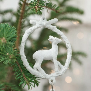 White reindeer resin Christmas ornament with glitter finish hanging on tree branches