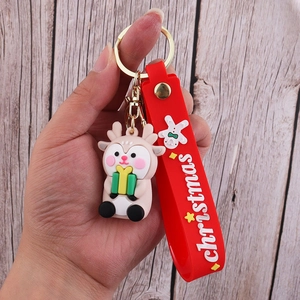 Detail of a beige Christmas reindeer keychain with a green gift box and red hand strap
