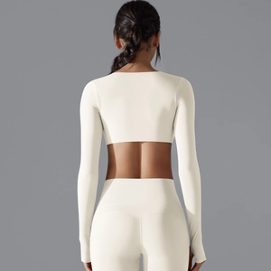 Dettaglio del crop top a maniche lunghe bianco panna e leggings yoga a vita alta