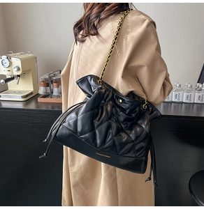 Close-up of black quilted bucket bag with chain strap and drawstring closure
