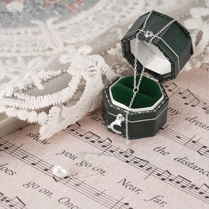 Detail of a white teardrop pearl pendant on a silver chain in a green velvet jewelry box