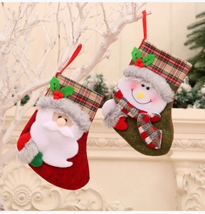 Detailed view of red Santa and green Snowman plush Christmas stockings with plaid accents