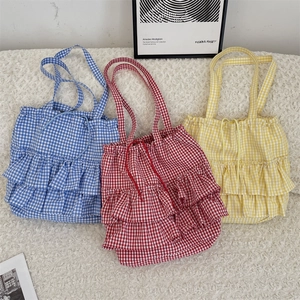 Three plaid canvas tote bags with ruffle edges in blue, red, and yellow colors