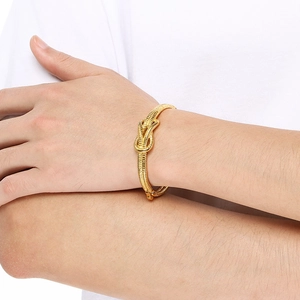 Close-up of a gold knotted cable bracelet featuring twisted texture on a female wrist