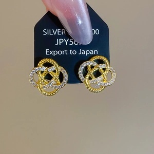 Gros plan de boucles d'oreilles trèfle en argent S925 doré serties de zircons sur carte
