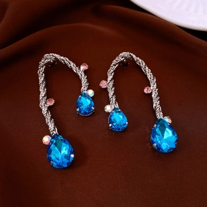 Macro shot of twisted silver earrings with blue teardrop crystals and pink zircon accents