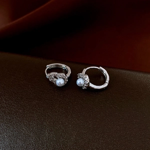 Detailed view of silver hoop earrings with white pearls and sparkling cubic zirconia stones