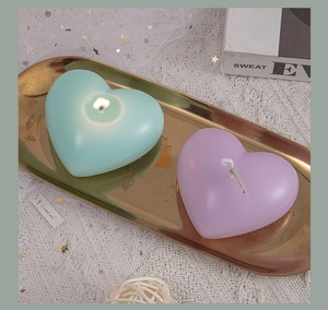 Close-up of heart-shaped scented candles in mint and lilac on a gold metal tray