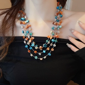 Detailed view of layered blue and brown shell bead necklace worn on model neck