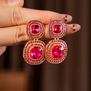 Close-up of vintage gold square earrings with faceted pink gemstones and crystals