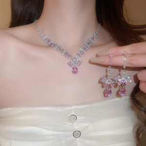 Close-up of elegant silver necklace and drop earrings set with pink teardrop crystals