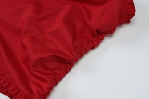 Close-up detail of red knitted fabric featuring ruched texture and ruffle design