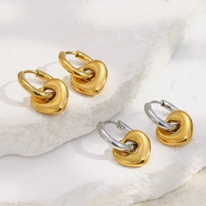 Vue détaillée des boucles d'oreilles cœur en or et bicolore sur fond de pierre