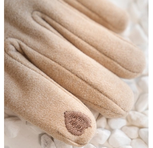 Dettaglio guanti in pile beige con ricamo a cuore marrone per l'uso del touchscreen