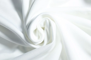 Détail macro du tissu en maille blanche montrant des drapés en spirale et des textures