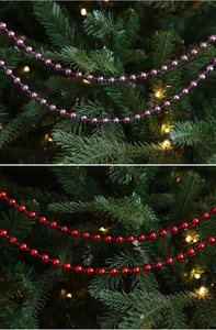 Macro detail of red and purple metallic bead garlands hanging on a Christmas tree
