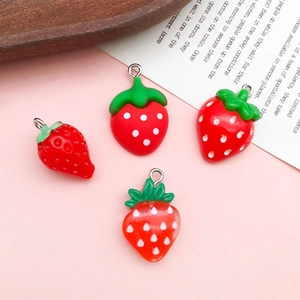 DIY red resin strawberry charms with green leaves and white dots on pink background