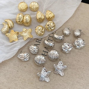 Detailed view of assorted gold and silver textured metal stud earrings in various shapes
