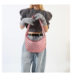 Close-up of metallic pink quilted dumpling bag shown with a grey winter outfit
