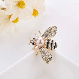 Detailed macro view of a vintage gold honey bee brooch with a pink pearl and rhinestones
