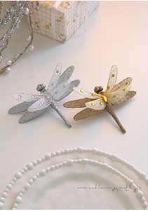 Dettaglio macro di libellule decorative glitterate con strass e finiture dorate