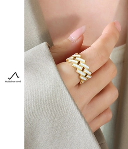Close-up of golden stainless steel ring with white enamel tiles worn by a model