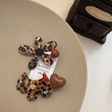 Detail of floral acetate hair clip and terrier motif with vintage leopard print patterns