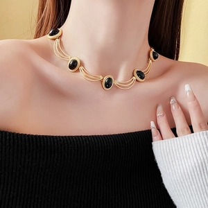 Elegant gold chain necklace featuring five black oval gemstones worn by a model