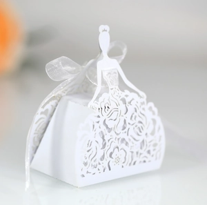 Detail of white laser-cut wedding favor box featuring floral patterns and a silk ribbon