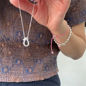 Close-up of minimalist 925 sterling silver knotted necklace and beaded bracelet